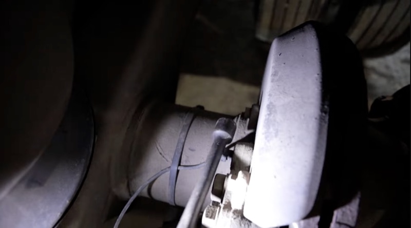 Close-up of a starter motor and exhaust components underneath a semi truck